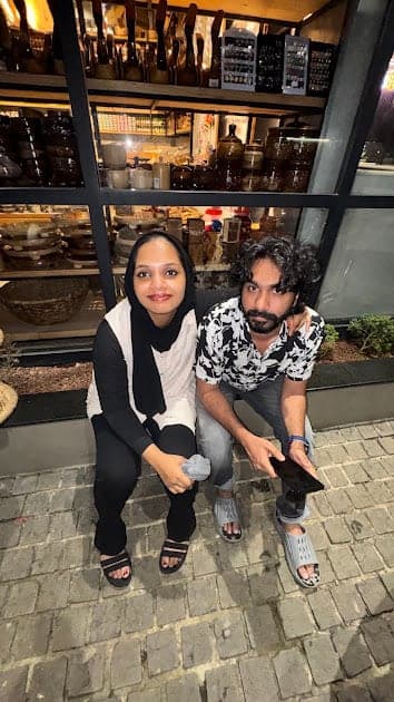 Fazna and Nisham sitting on a ledge in a city at night