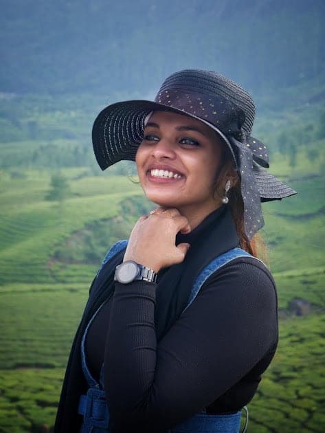Fazna smiling in a hat, tea bushes behind