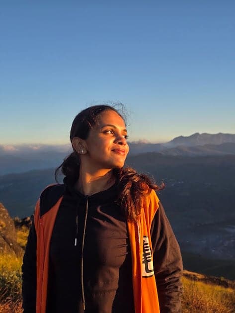 Fazna in an orange jacket at sunrise in the hills