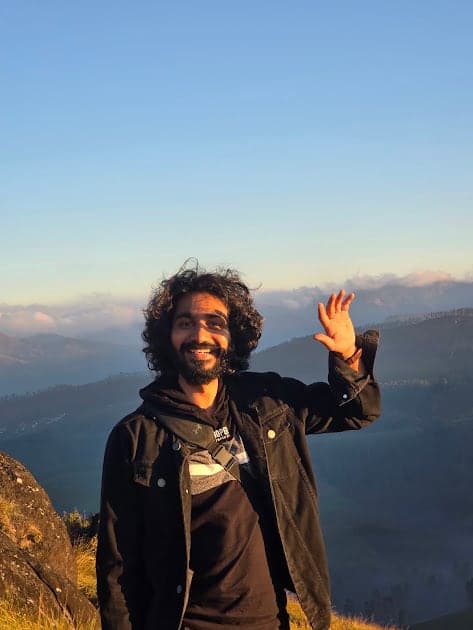 Nisham waving on a hilltop at sunrise